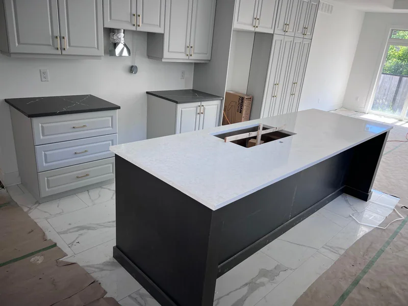 A TSF installation with white stone on a dark island and dark perimeter countertops